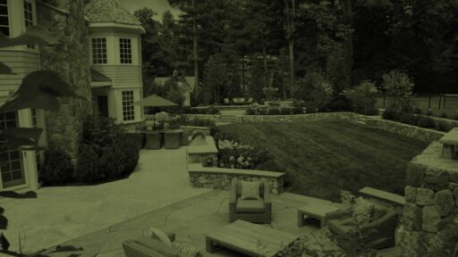 A thoughtfully designed Needham landscape with stone terraces, lawn, layered plantings, and inviting outdoor living spaces.