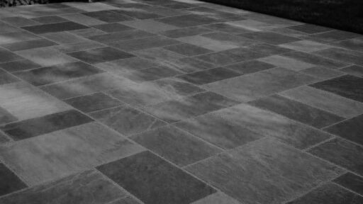 Belmont, MA - This dry-laid bluestone patio shows how frost heave, poor drainage, or an unstable base can cause individual stones to lift, sink, or rock after winter.