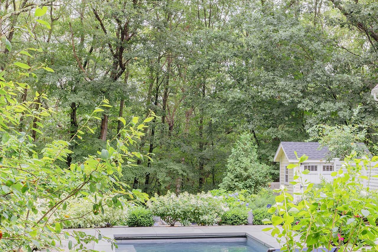 Framed by soft planting and woodland views, the pool lounge terrace offers a quiet outdoor room designed for relaxation and seasonal enjoyment, copyright: Michael J Lee