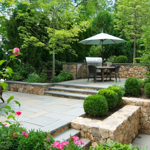 A Wellesley stone patio and terrace design uses masonry steps, layered grade changes, and elegant planting to connect the home and garden.