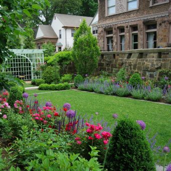 Brookline, MA - A mixed border of bulbs, perennials, and flowering and evergreen shrubs help to define an emerald green lawn.