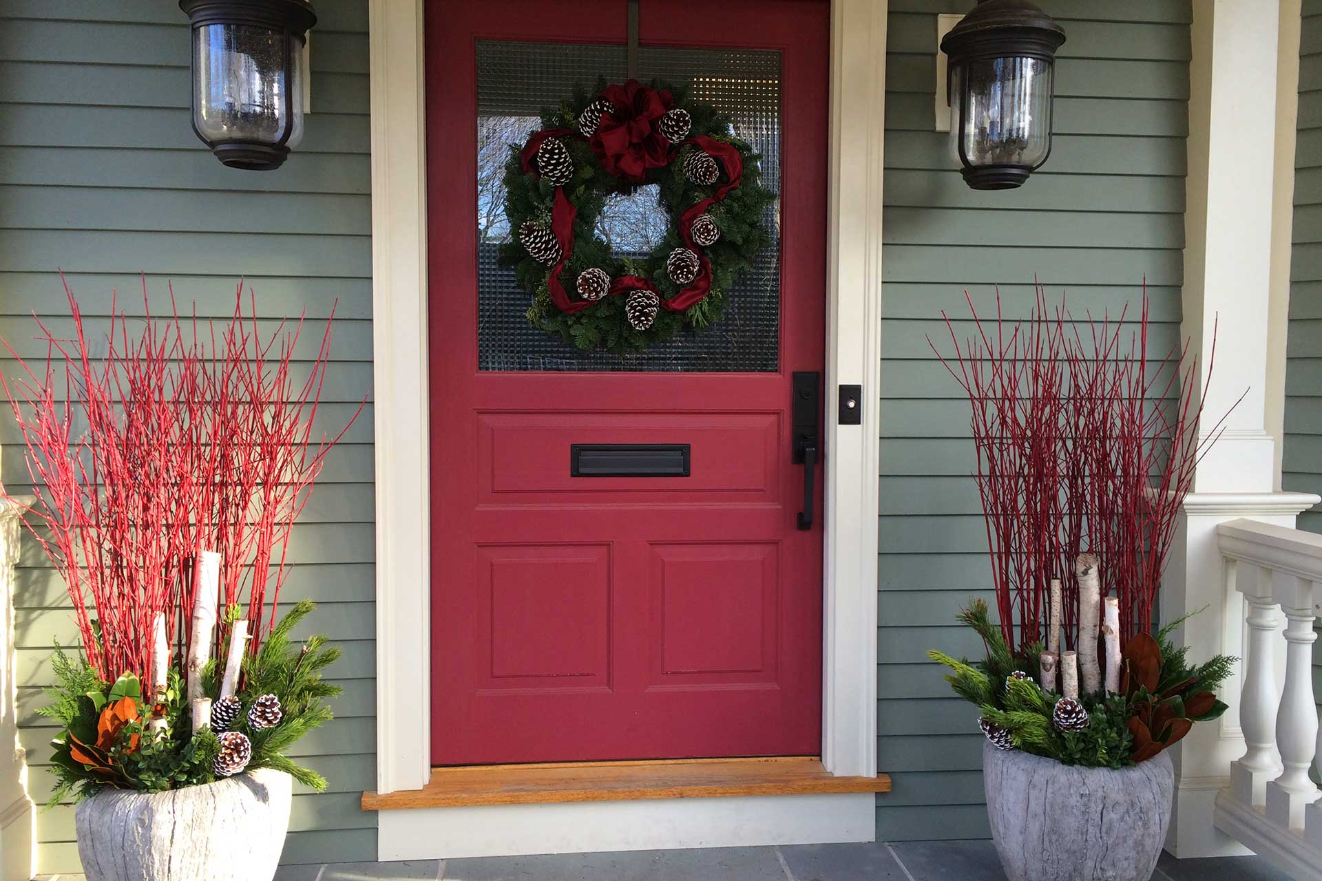 A red-accented wreath adds festive color and instant charm, drawing the eye to the front door without excess decoration.