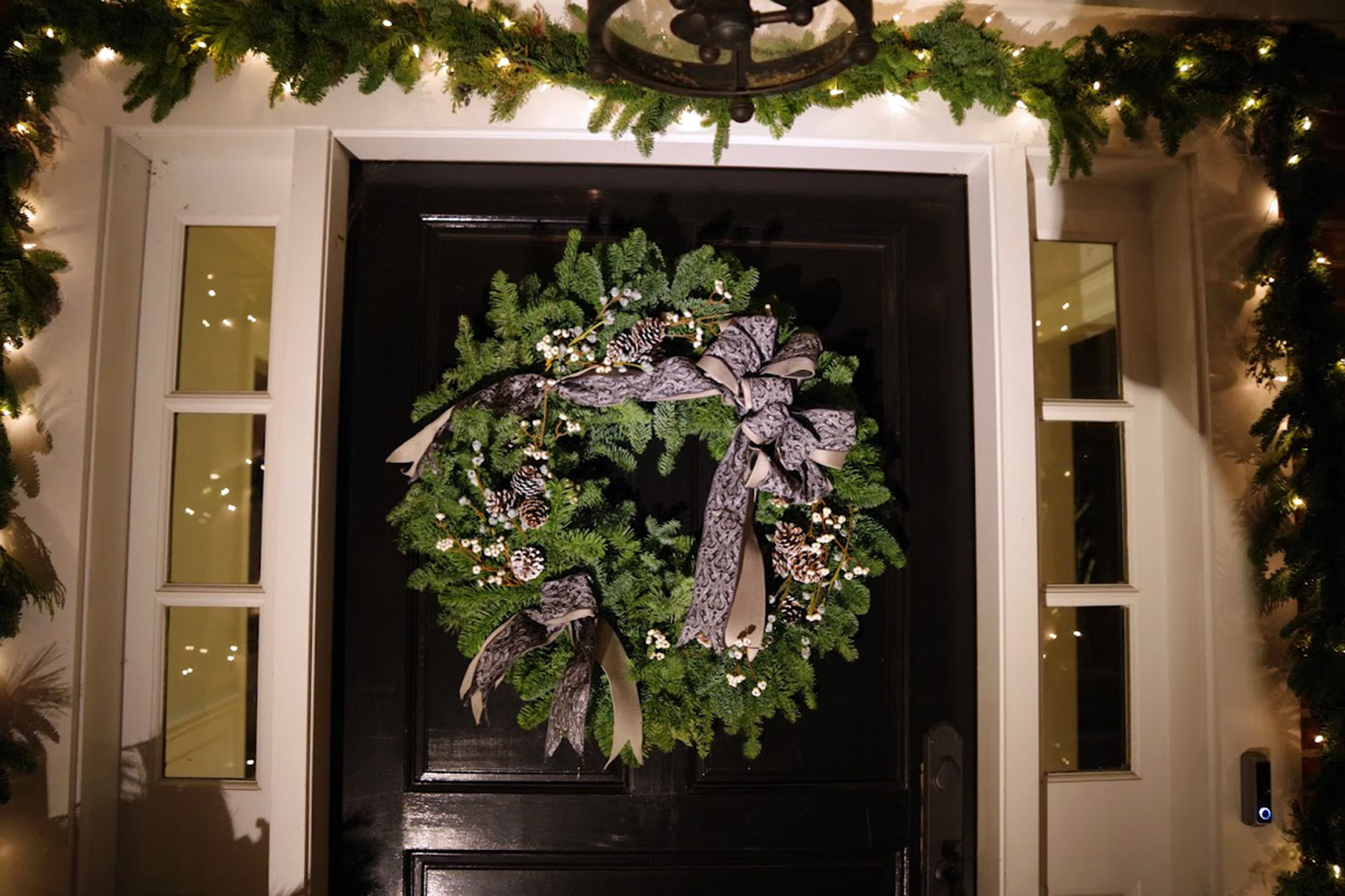 Layered evergreens and ribbon create an elegant wreath that elevates the entry with subtle detail and timeless seasonal appeal.