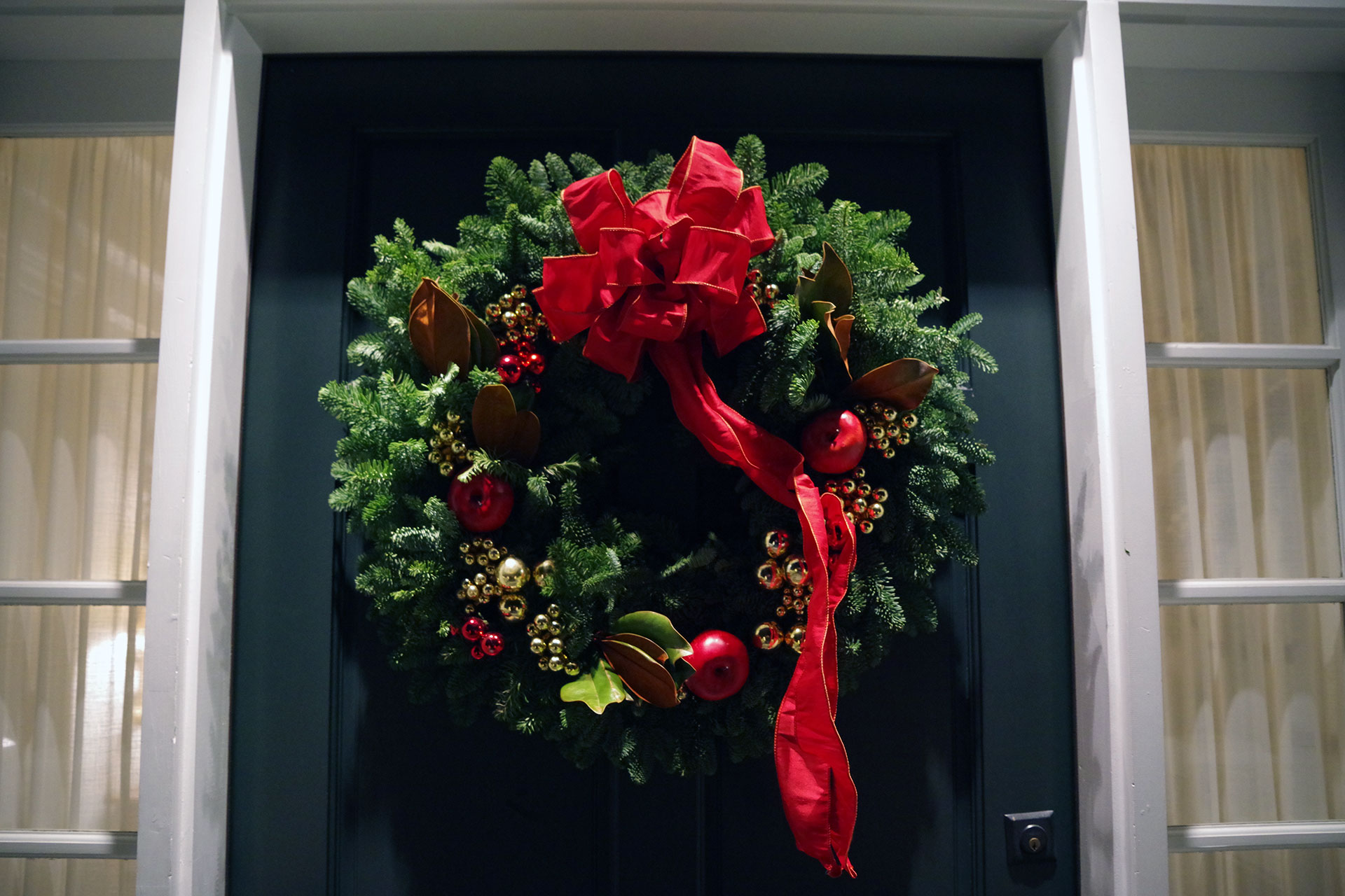 Dense evergreen foliage frames the door beautifully, delivering simple holiday style that complements traditional Boston architecture.