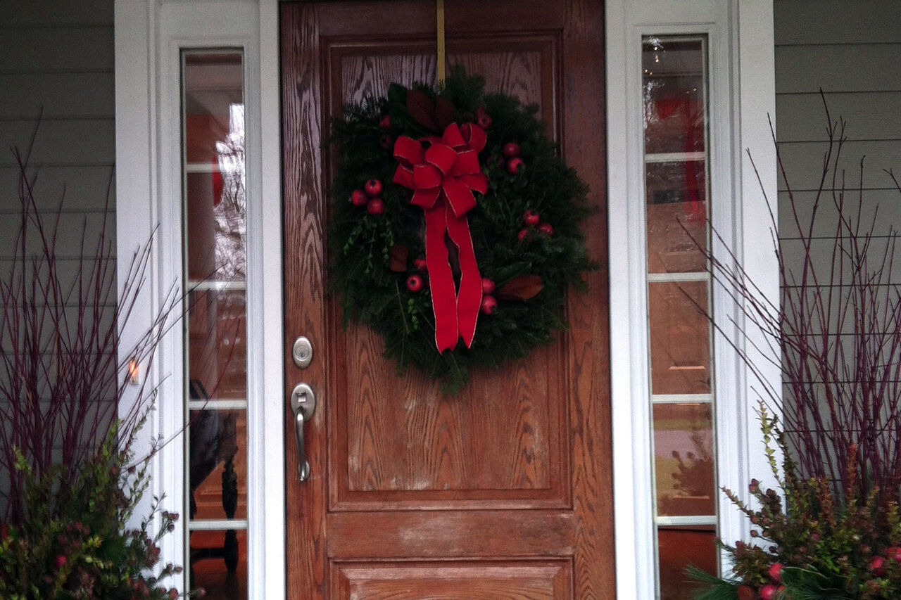 A classic evergreen wreath adds a festive yet restrained touch, enhancing the front door with natural color and texture.