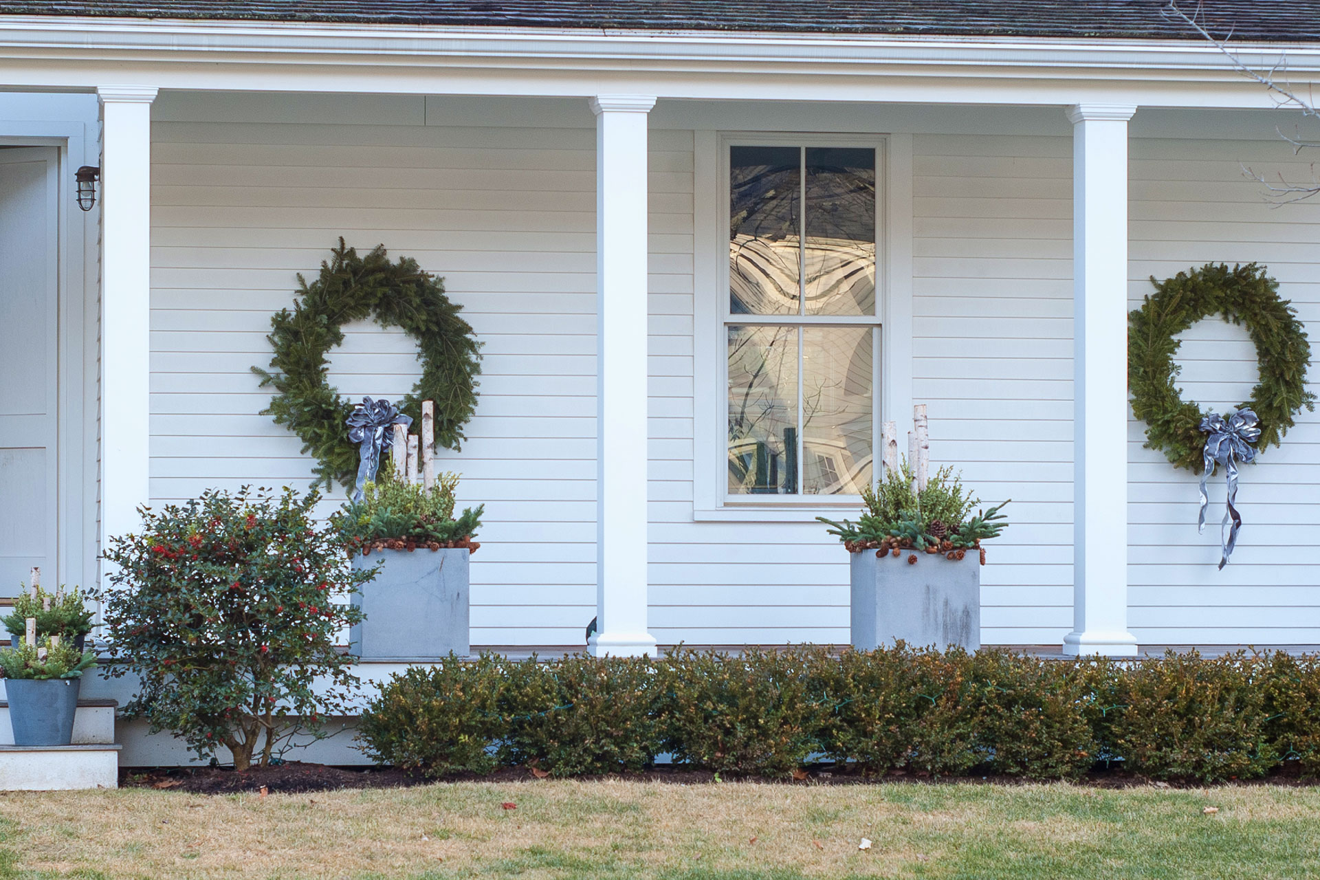 Paired wreaths create symmetry and balance on the porch, reinforcing the home’s architecture with simple, seasonal greenery.