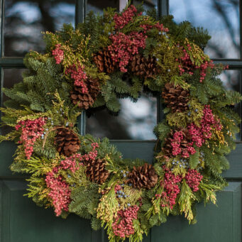 Fresh evergreen wreath with winter berries adds natural color and understated holiday charm, complementing classic New England entry doors.