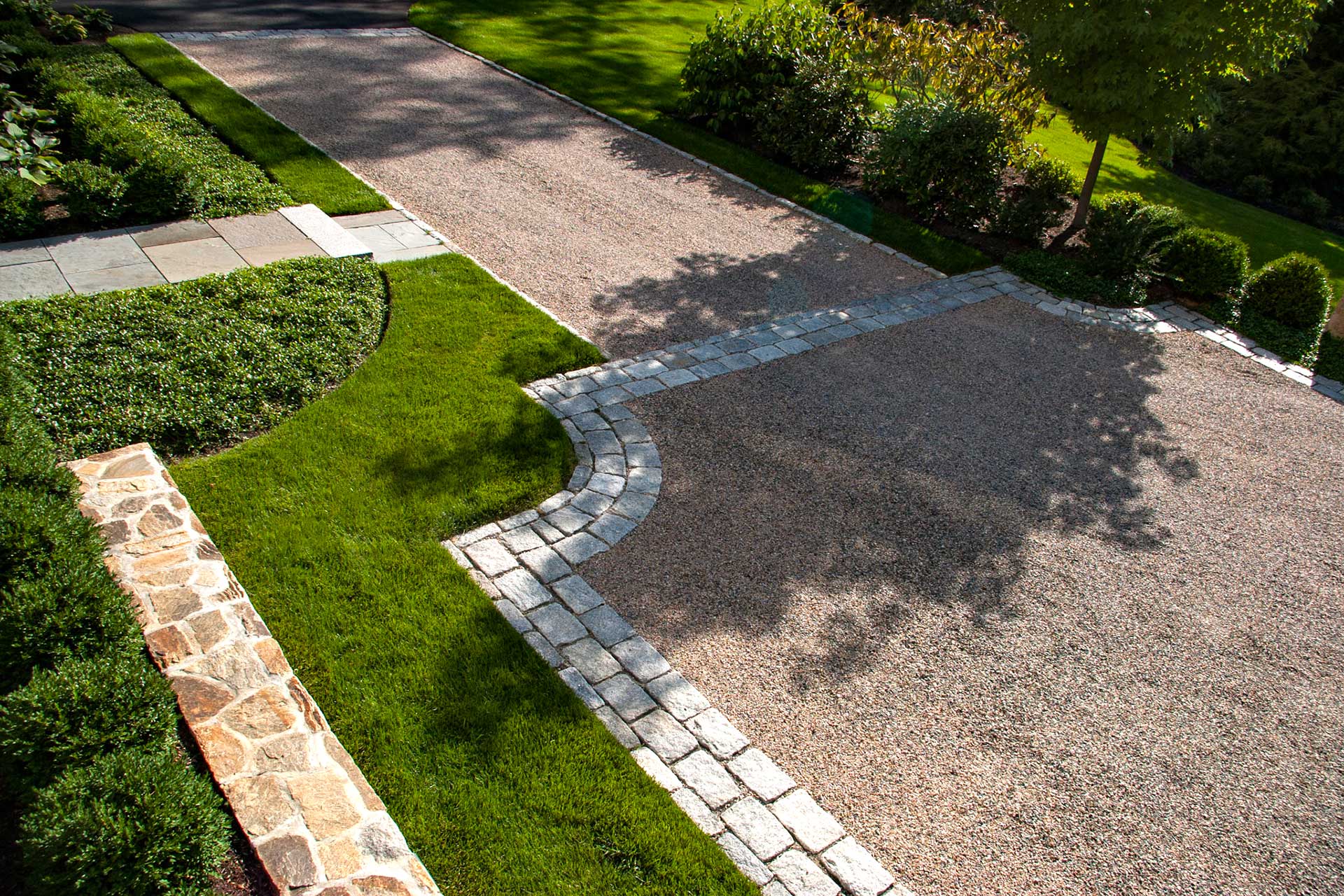 A circular gravel driveway at a coastal estate is defined by stone borders, offering durability and a clear sense of arrival that complements open surroundings.