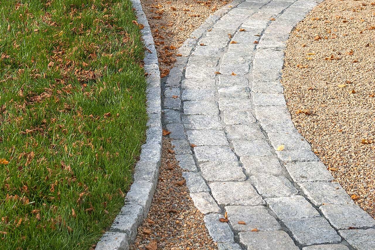 This curved gravel driveway detail highlights stone edging that controls material migration while reinforcing smooth transitions and clean lines at key turning points.
