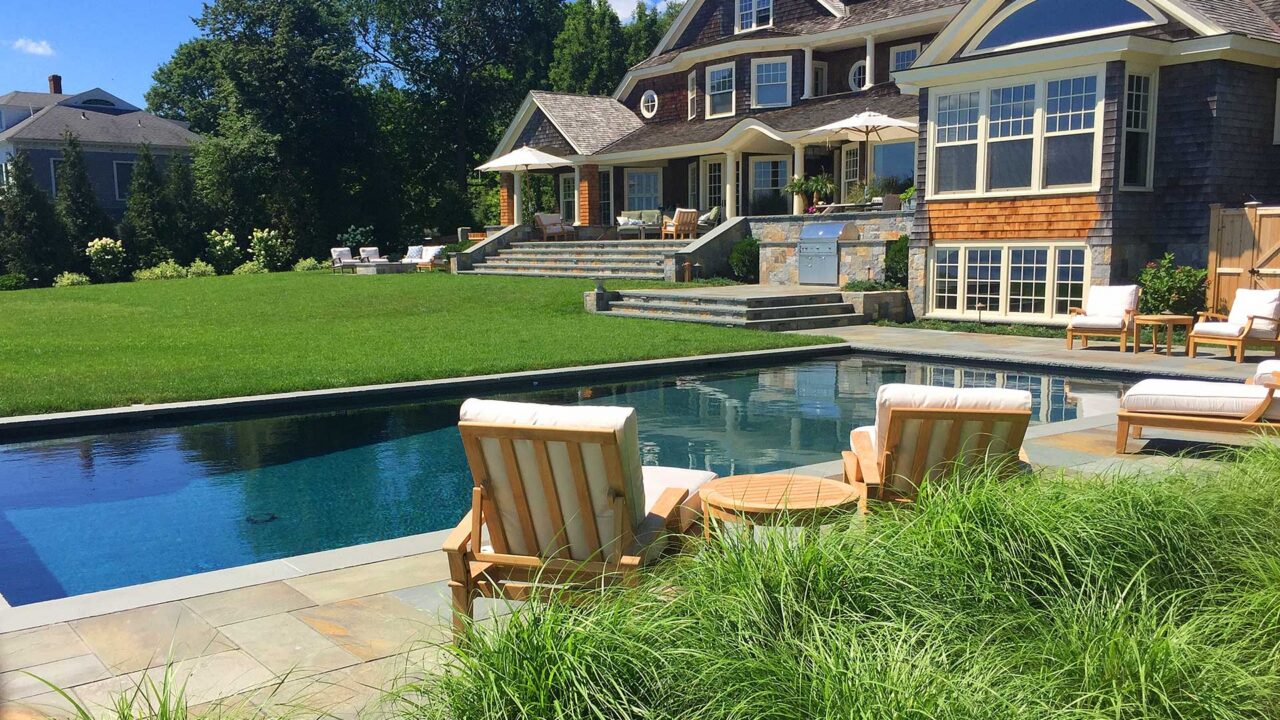 Duxbury, MA - A backyard retreat complete with an in ground pool, lush lawn and plantings, bluestone surfaces, and a built in kitchen.