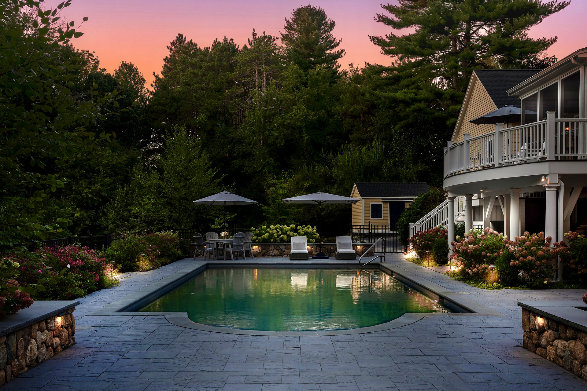 Garden bed uplighting adds depth and structure while softly illuminating the pool surroundings.