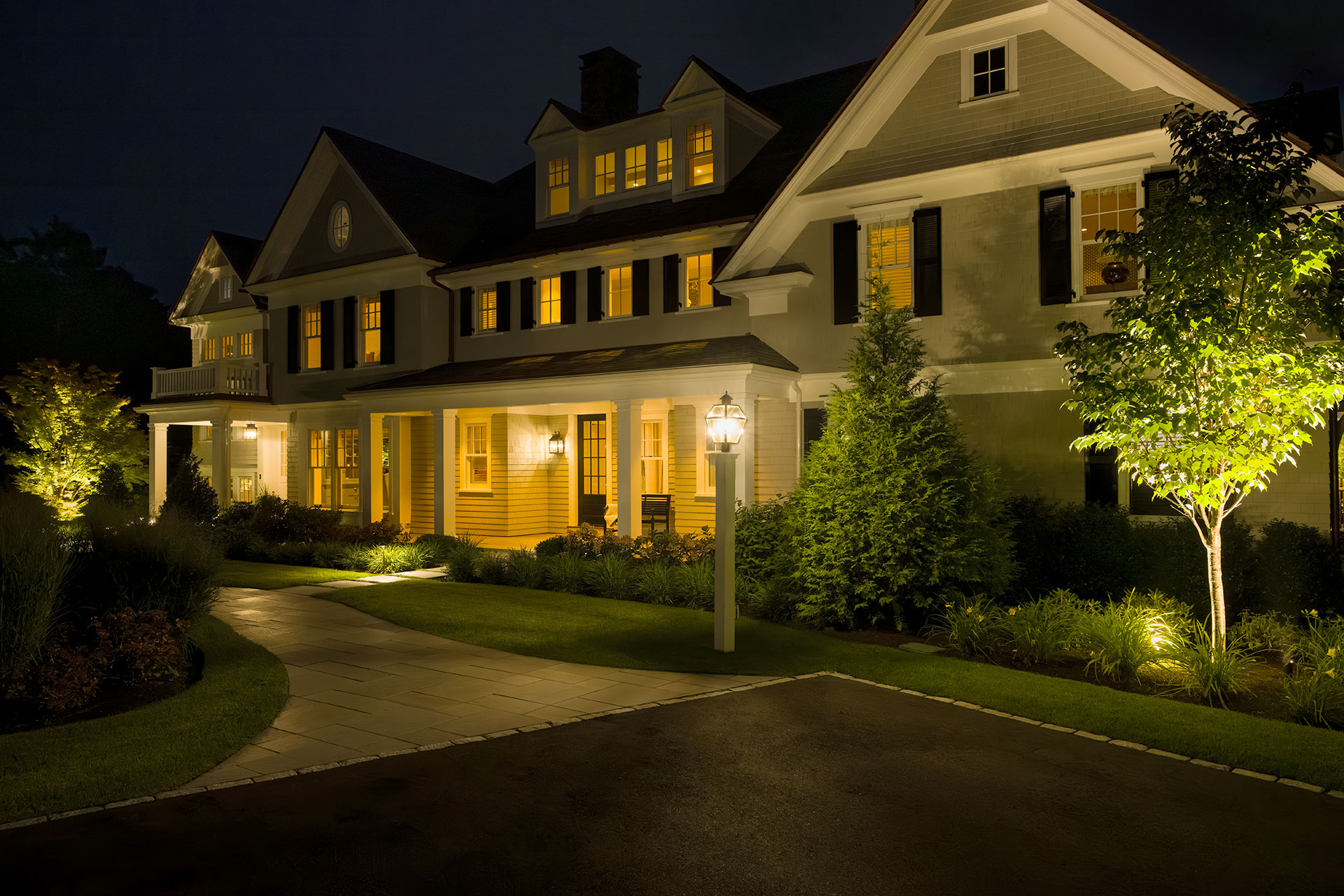 Facade and pathway lighting guide arrival while highlighting architectural details and layered planting.