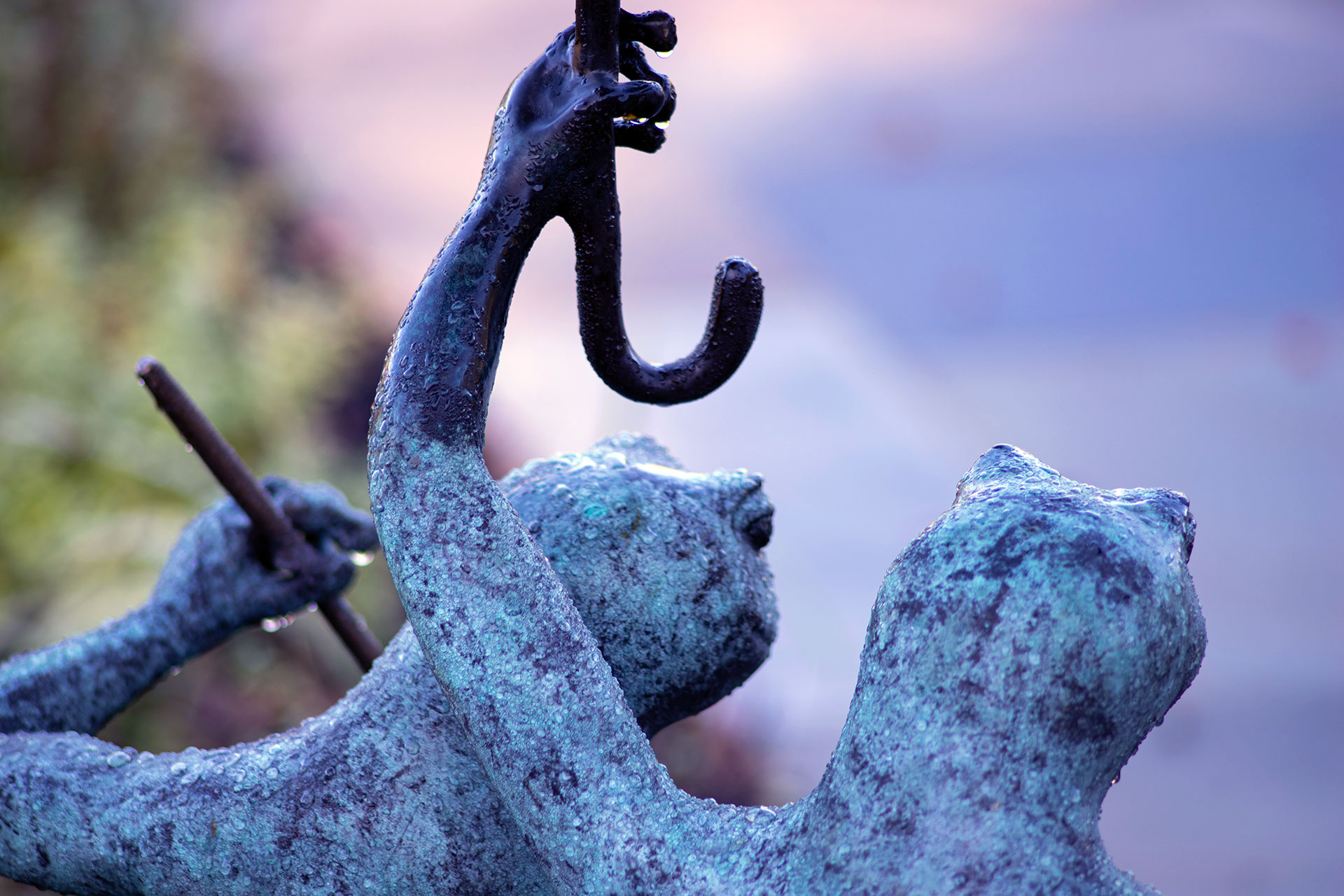 This bronze figurative sculpture features a weathered patina and expressive form, offering artistic depth and a strong focal point within the garden composition.