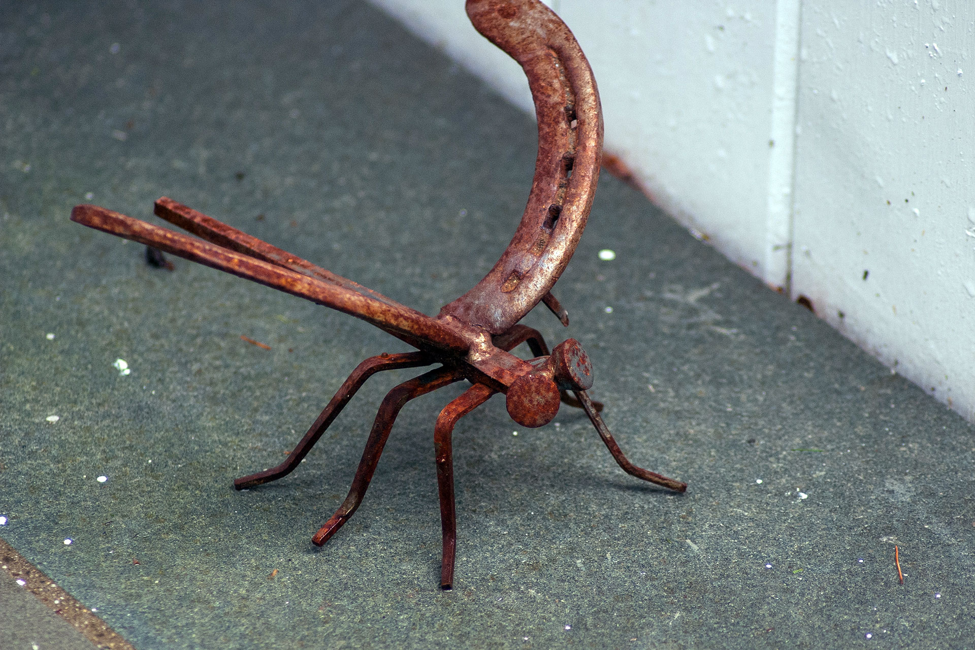 A handcrafted metal insect sculpture with a weathered steel finish adds fine detail and whimsy to the patio, inviting close inspection and subtle visual interest.