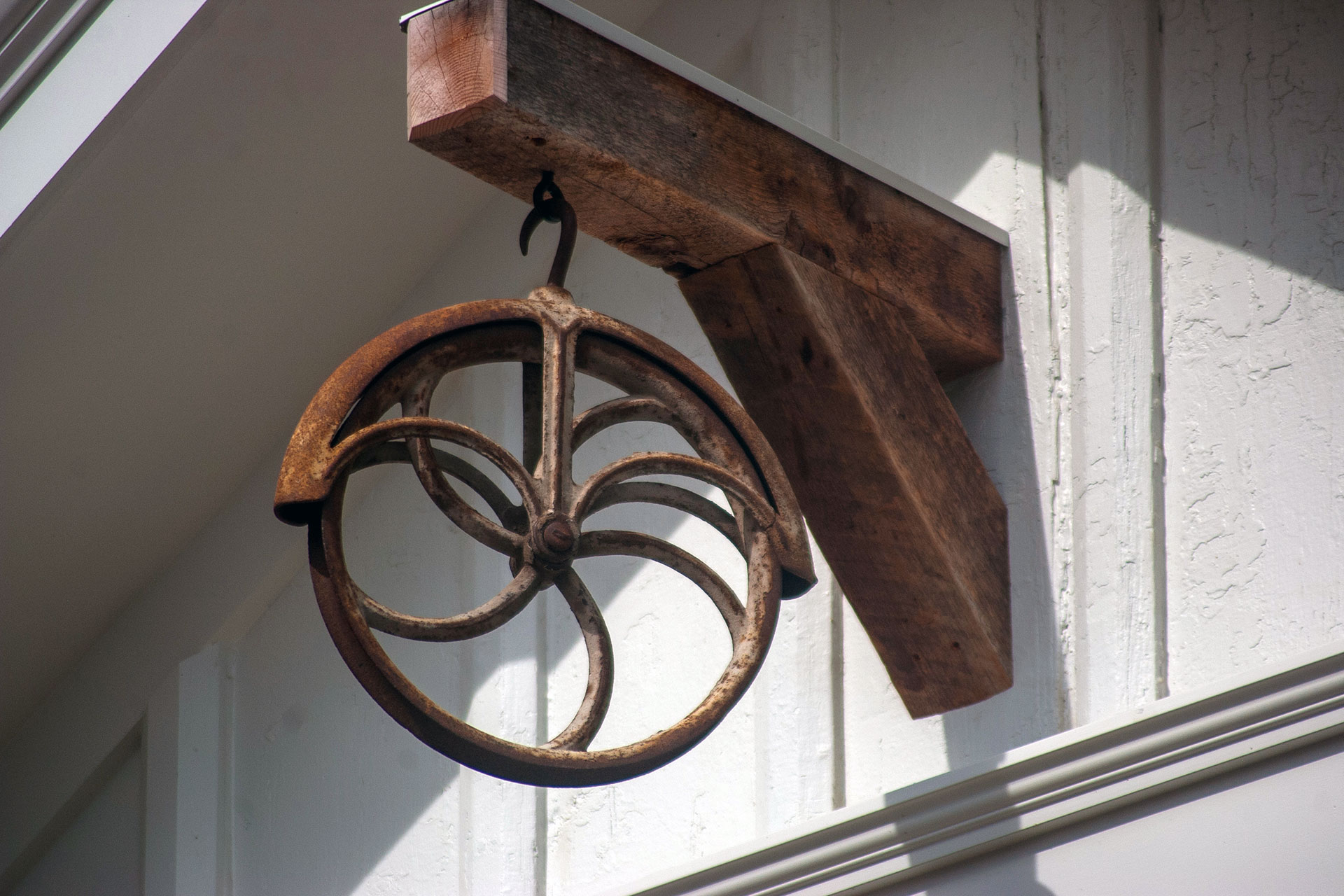 This rustic iron pulley ornament nods to New England farmhouse heritage, adding industrial texture and historic charm when displayed as a garden or porch accent.