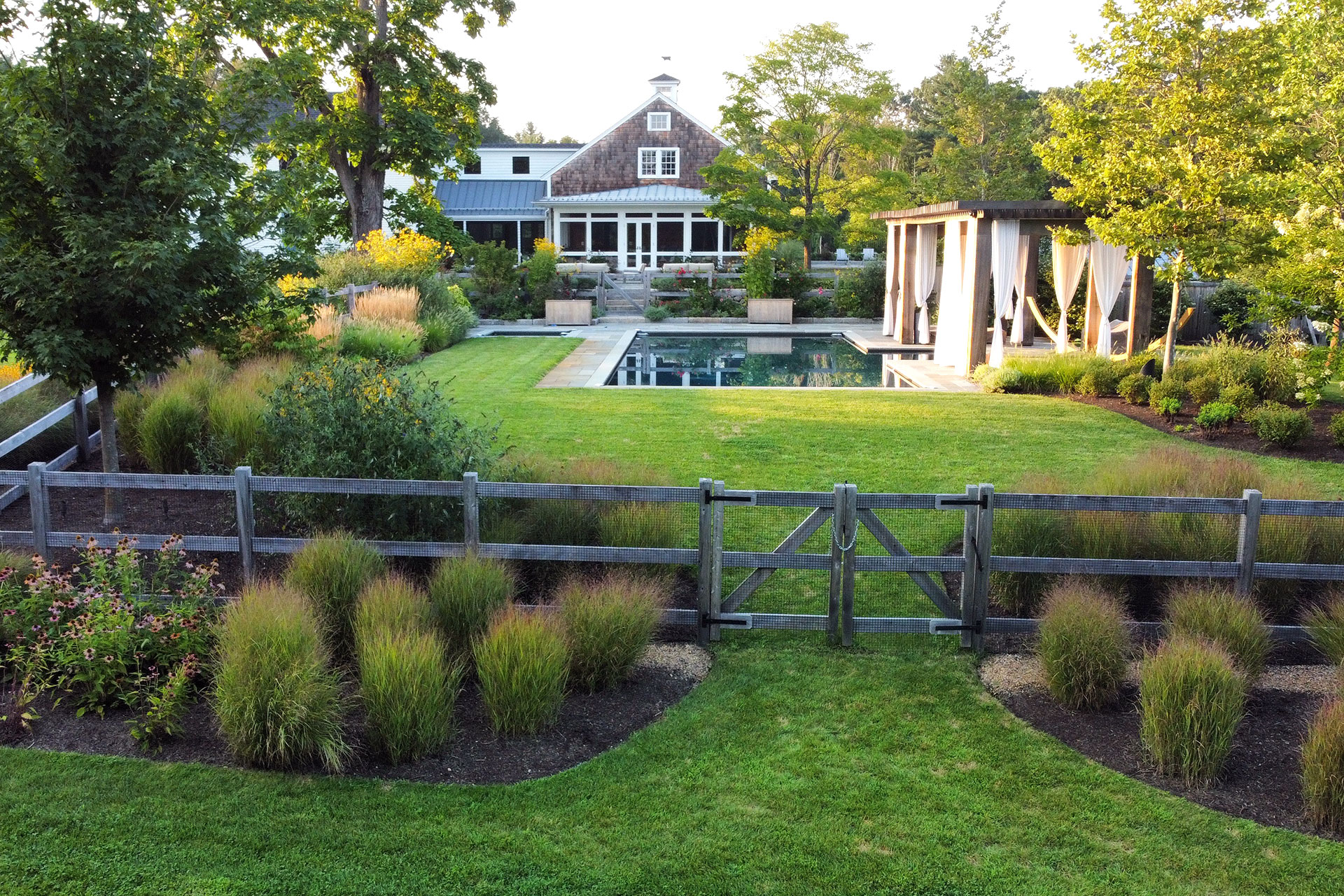 A low-profile wood fence organizes the garden boundary, protecting beds and guiding movement without closing off the landscape.