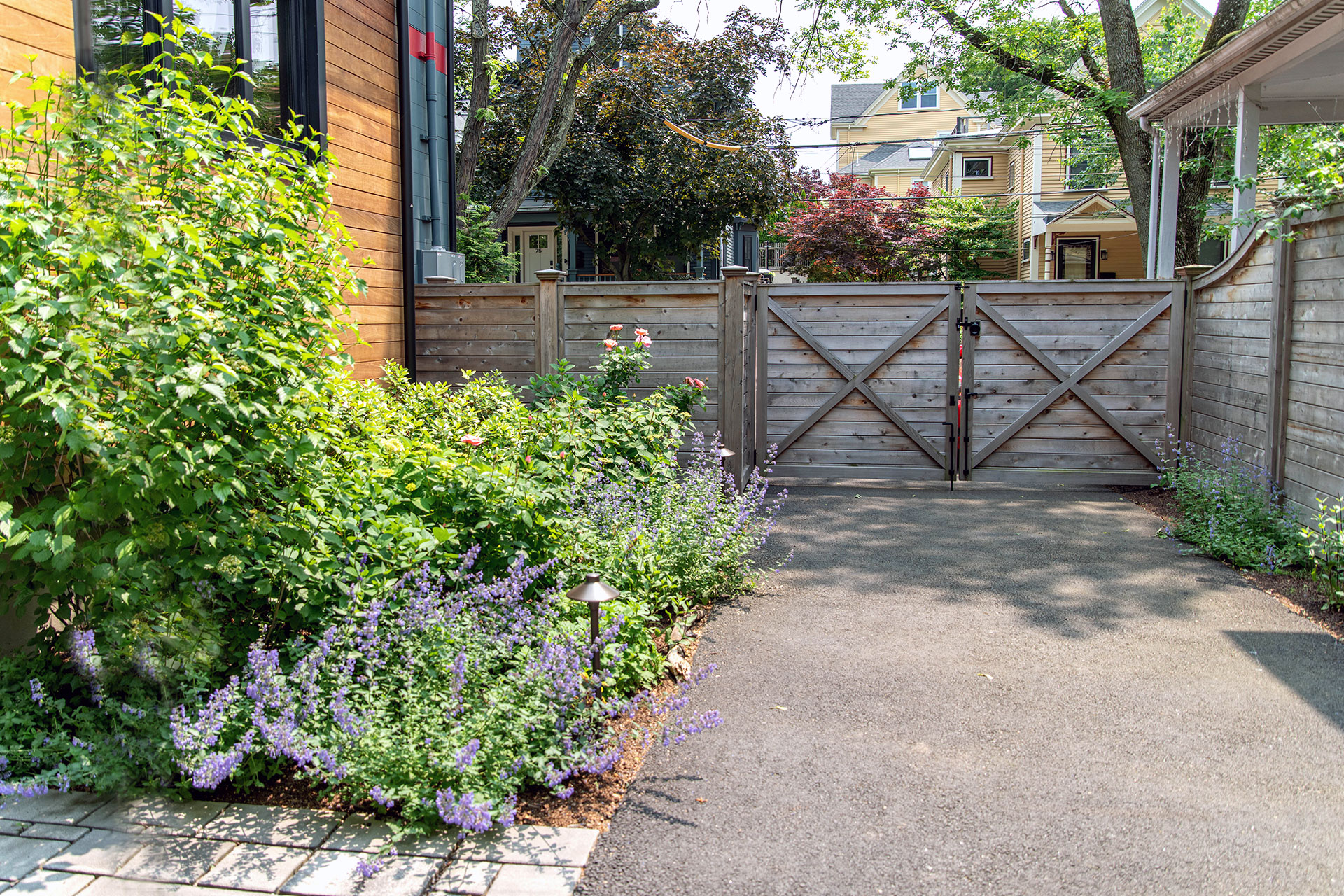 A horizontal wood driveway fence and gate manage entry and limit street exposure, creating a more private and secure residential setting.