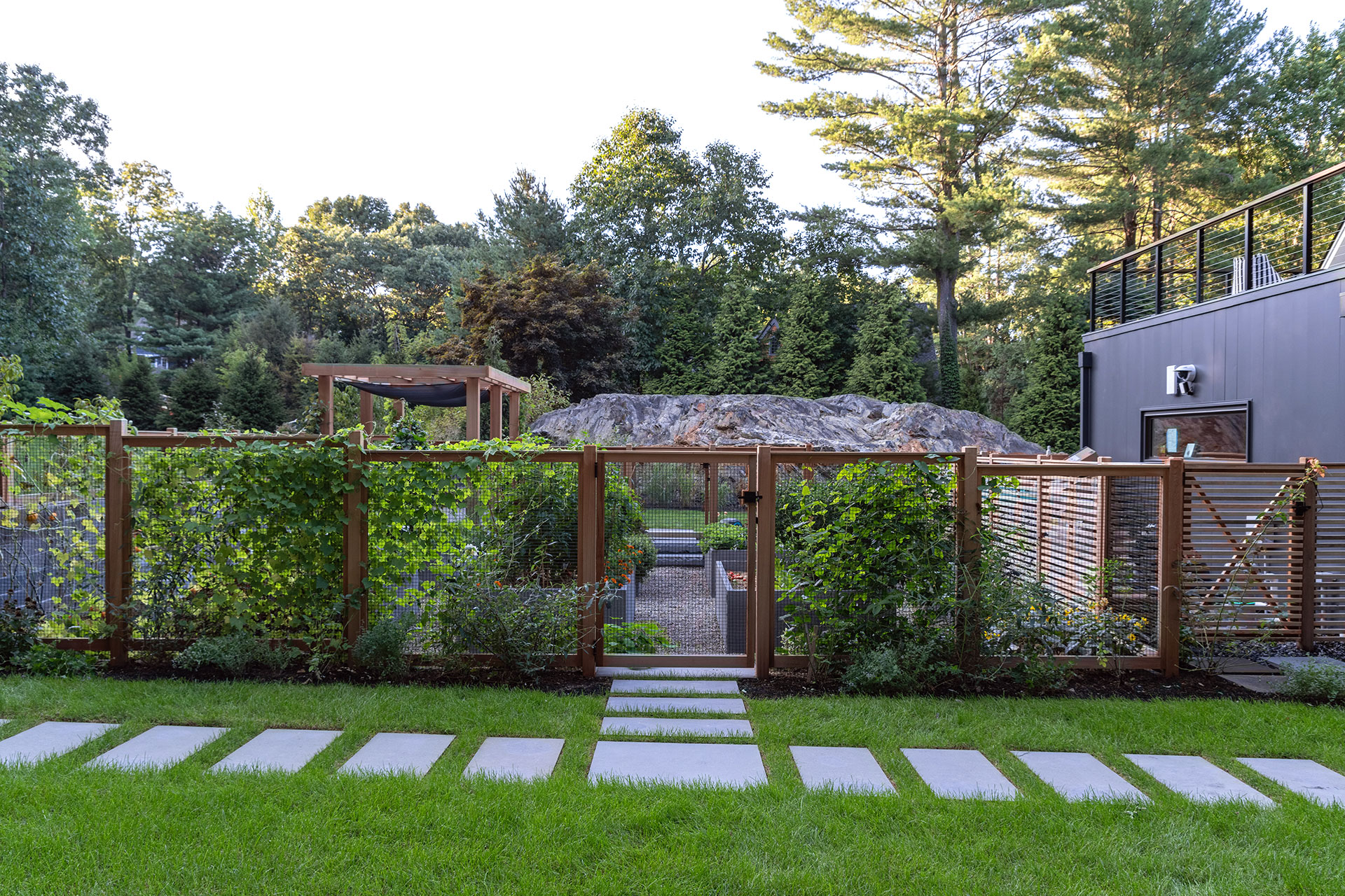 A modern wood and wire fence suits this Dover landscape, providing security while maintaining clean, contemporary lines.
