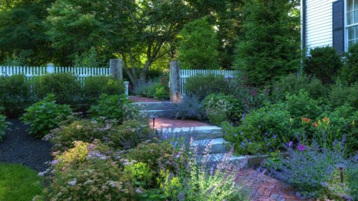 This Lincoln garden pairs lush planting beds with natural stone edging for a refined, well-structured New England landscape.