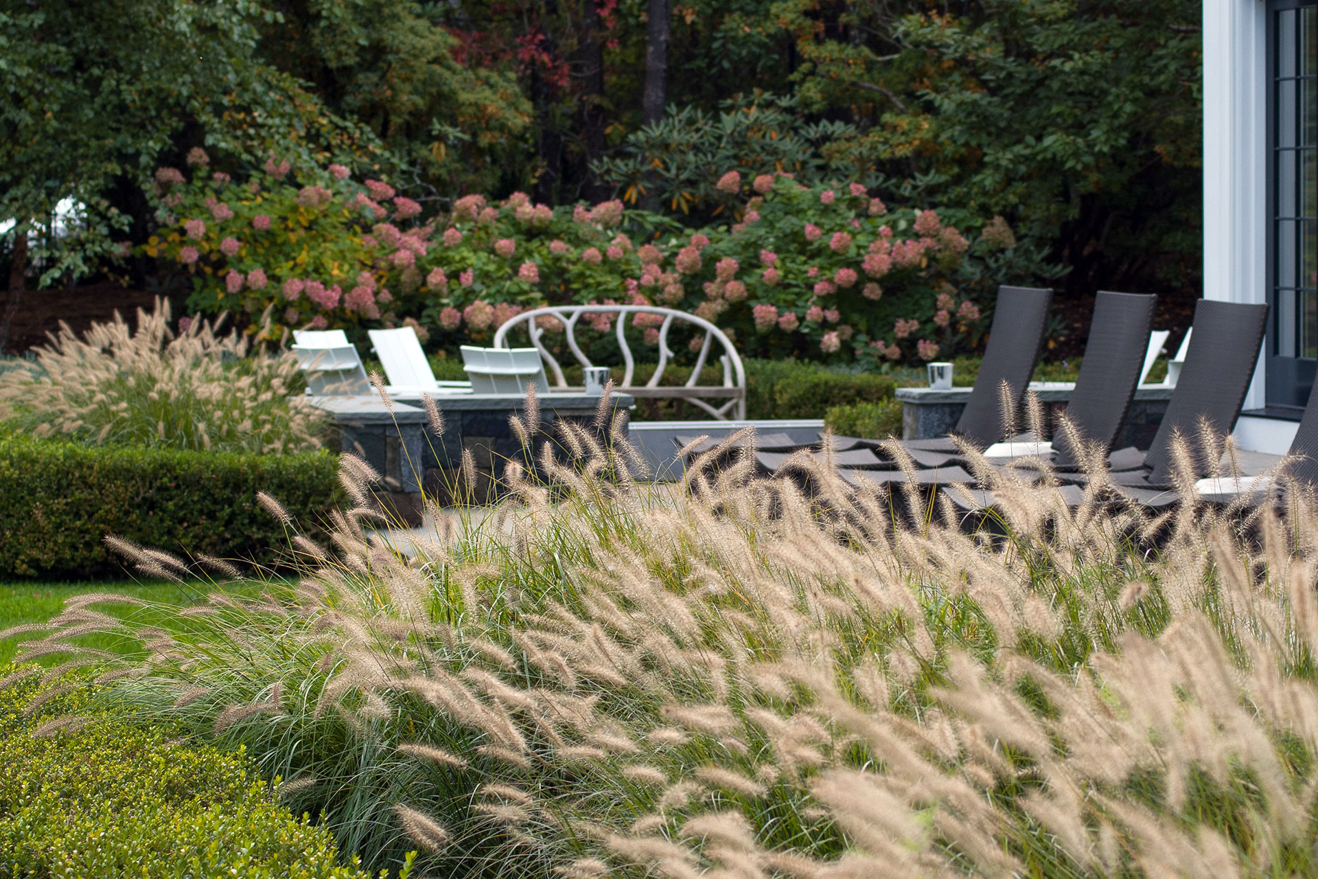 Low, flowing ornamental grasses frame this poolscape in Dover, softening stone edges while providing year-round structure with minimal maintenance.