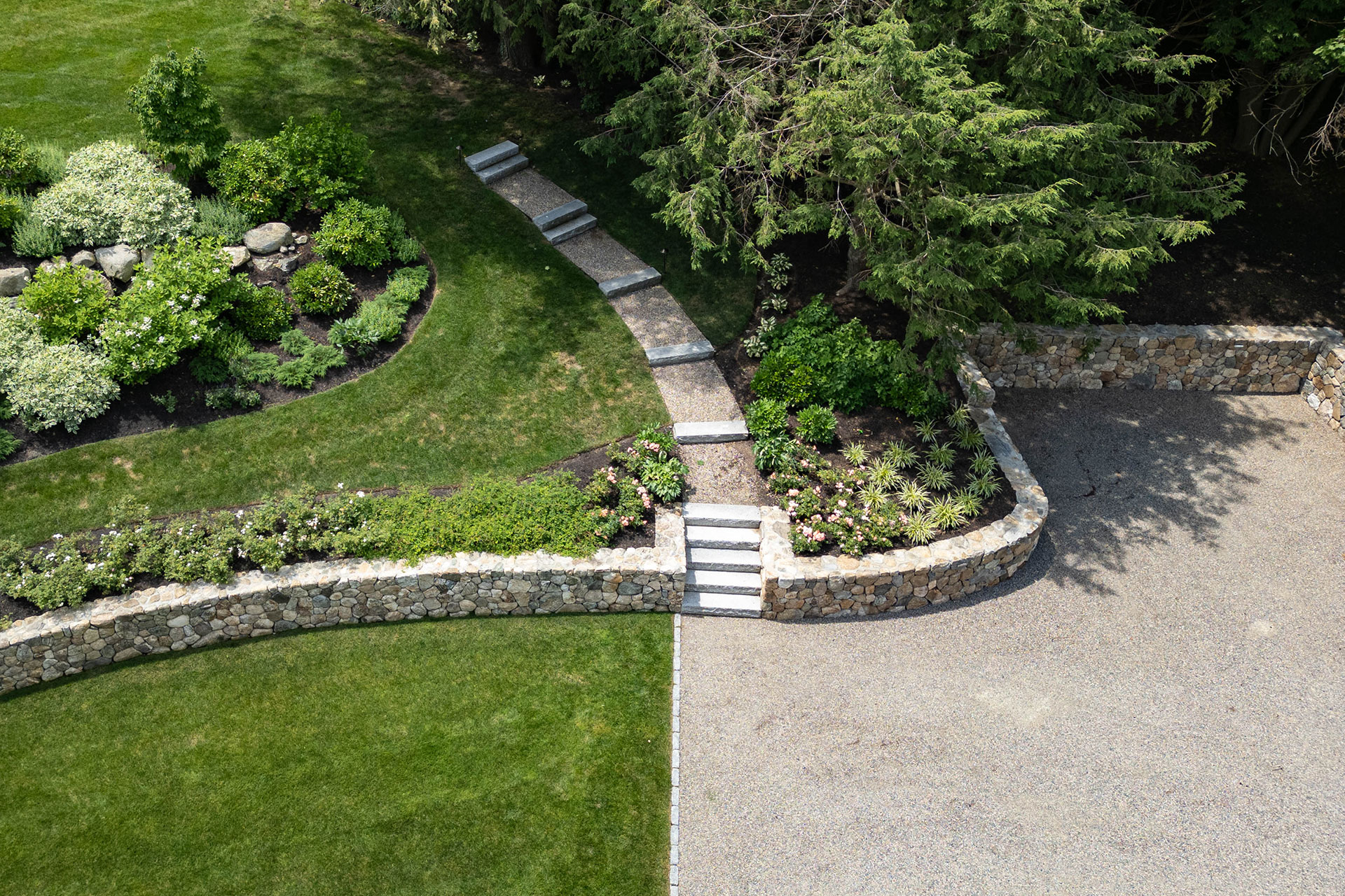Gravel garden path curves alongside bluestone steps and retaining walls, managing grade with a natural feel.