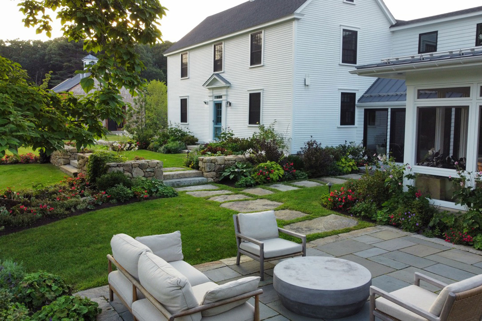 Large stone steppers form a relaxed front walkway, balancing durability with a lighter footprint that softens the home’s formal architecture.