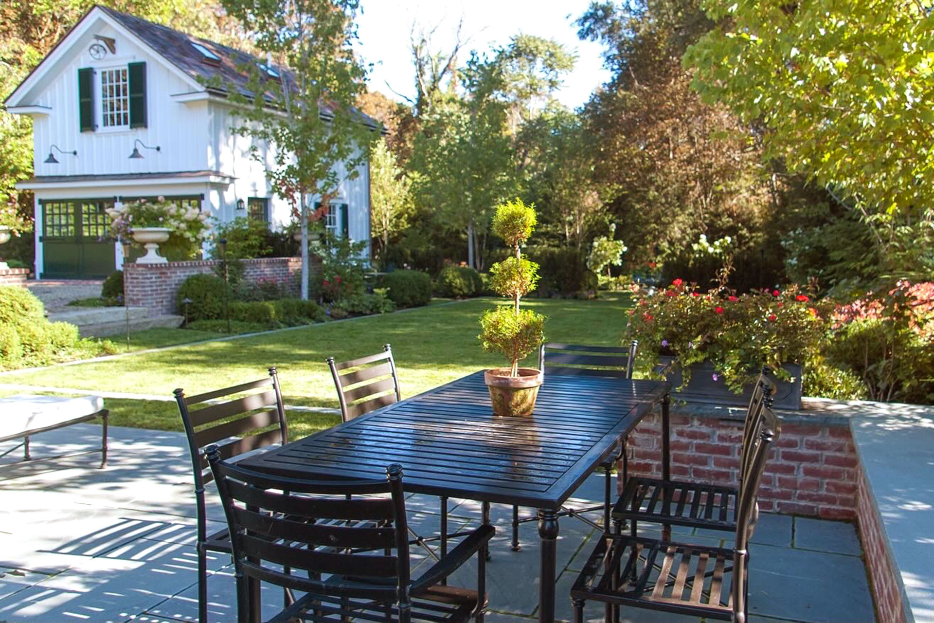 Classic backyard patio with brick walls and dining table combines traditional hardscape with comfortable outdoor living for family meals and entertaining.