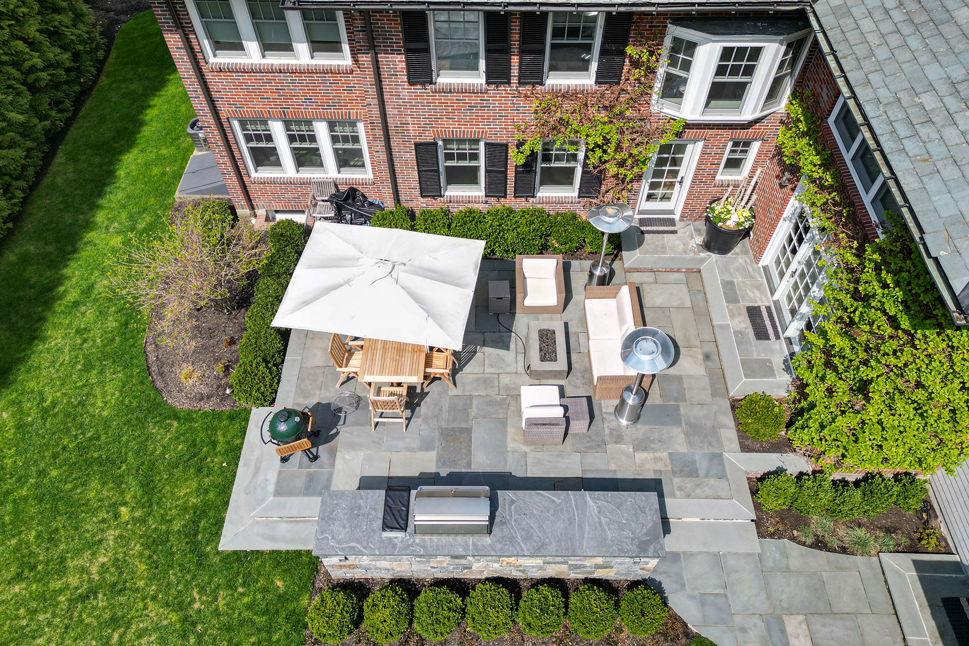 Compact city patio with outdoor kitchen and firepit integrates functional amenities into tight outdoor space for social cooking and lounging.