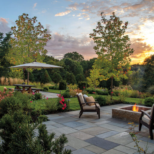 Firepit patio with sunset views and mountain‑style hardscape creates dramatic ambiance and rugged charm for cooler evenings outdoors in Dover.
