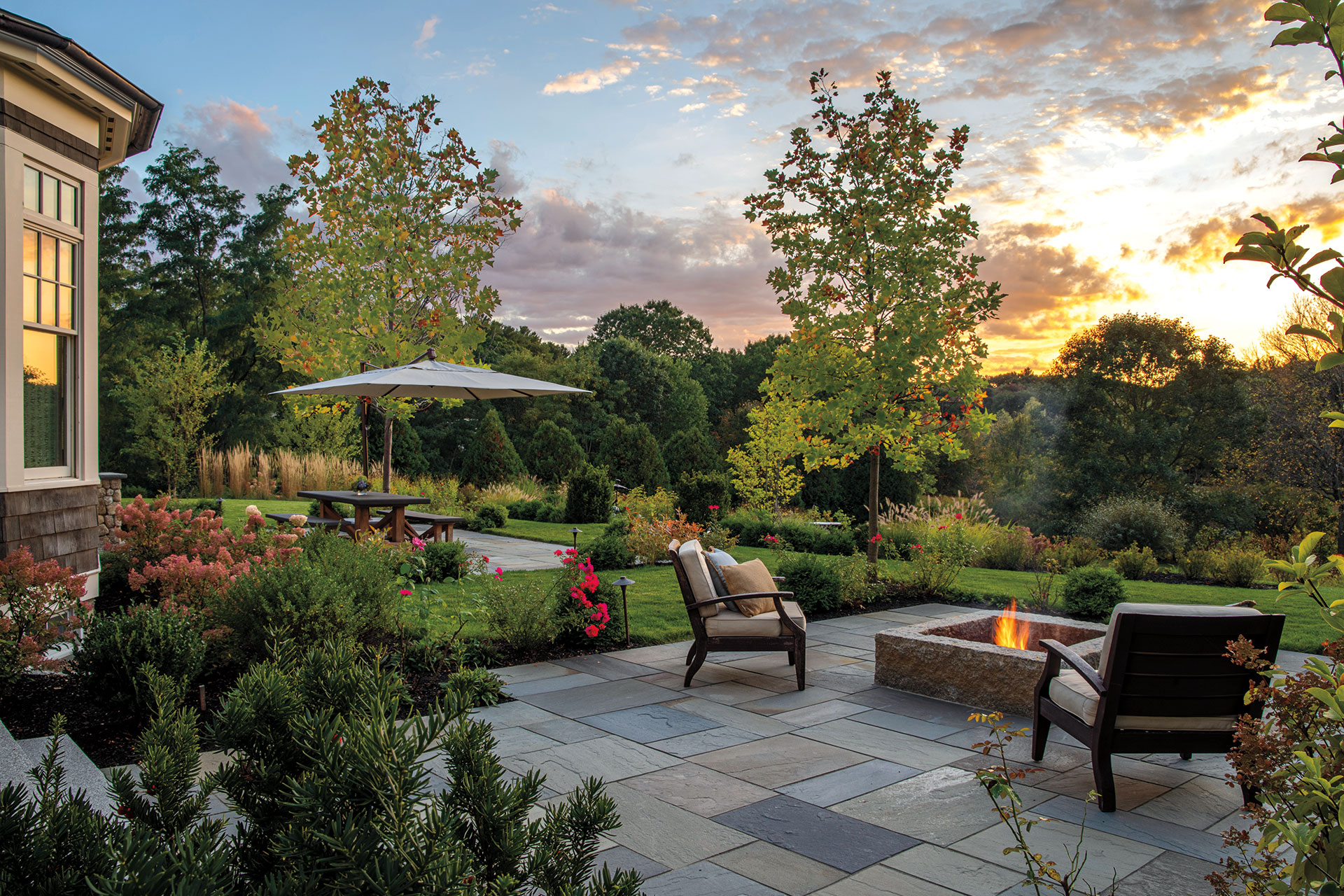 Firepit patio with sunset views and mountain‑style hardscape creates dramatic ambiance and rugged charm for cooler evenings outdoors in Dover.