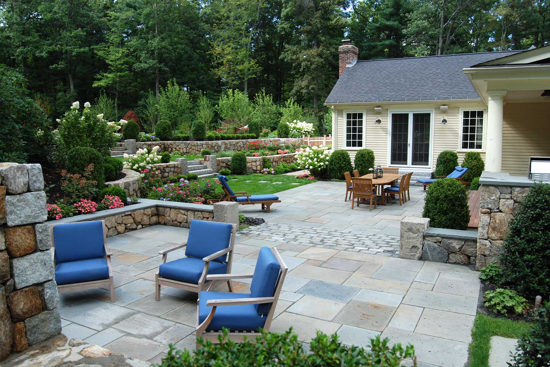 Tiered bluestone patio with distinct lounge and dining zones adds structure and elegance, ideal for outdoor entertaining and garden viewing in Dover settings.