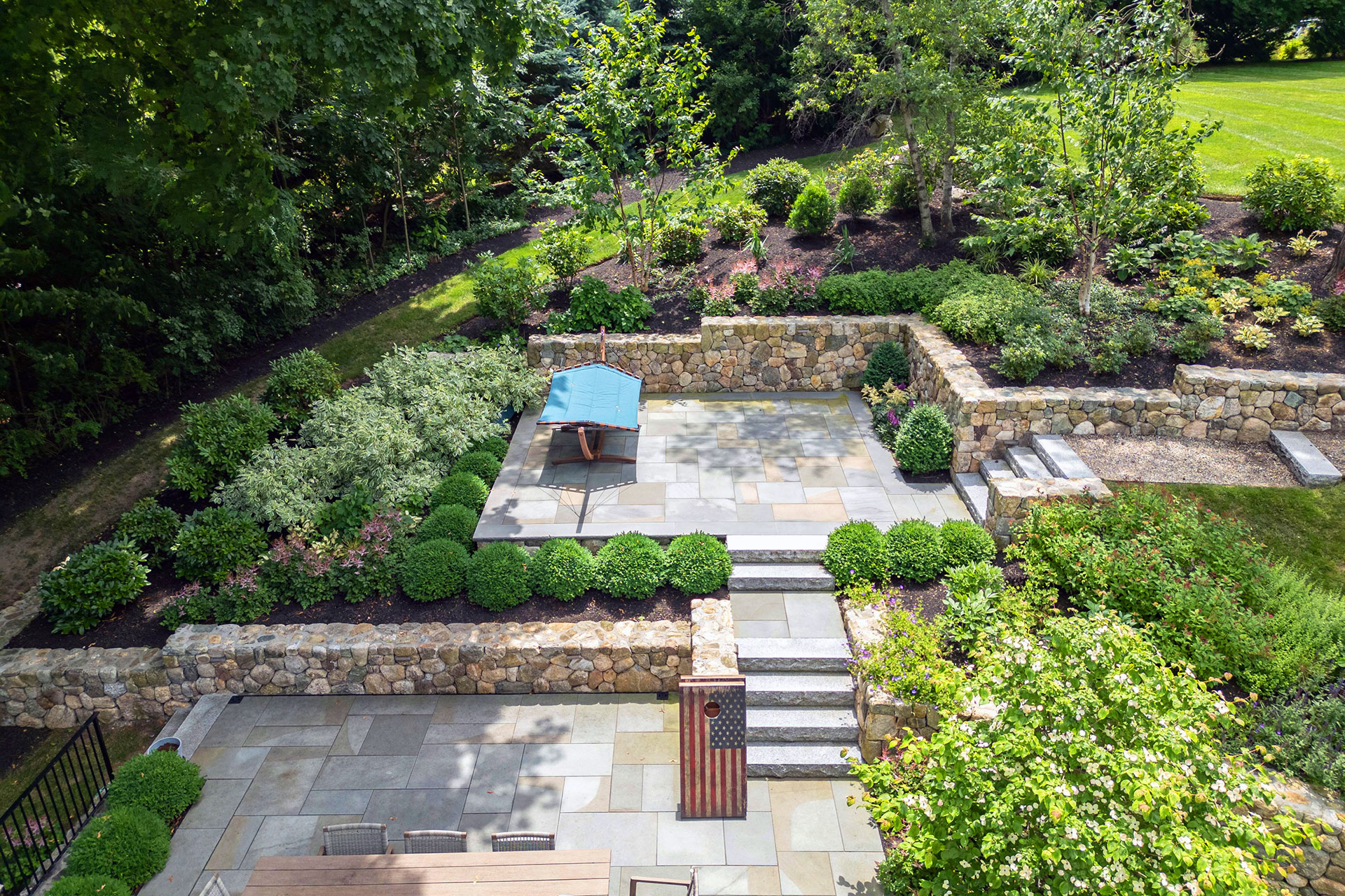 Multi‑level terrace with stone walls and a secluded seating nook blends natural texture and thoughtful layout for cozy relaxation amid lush plantings.