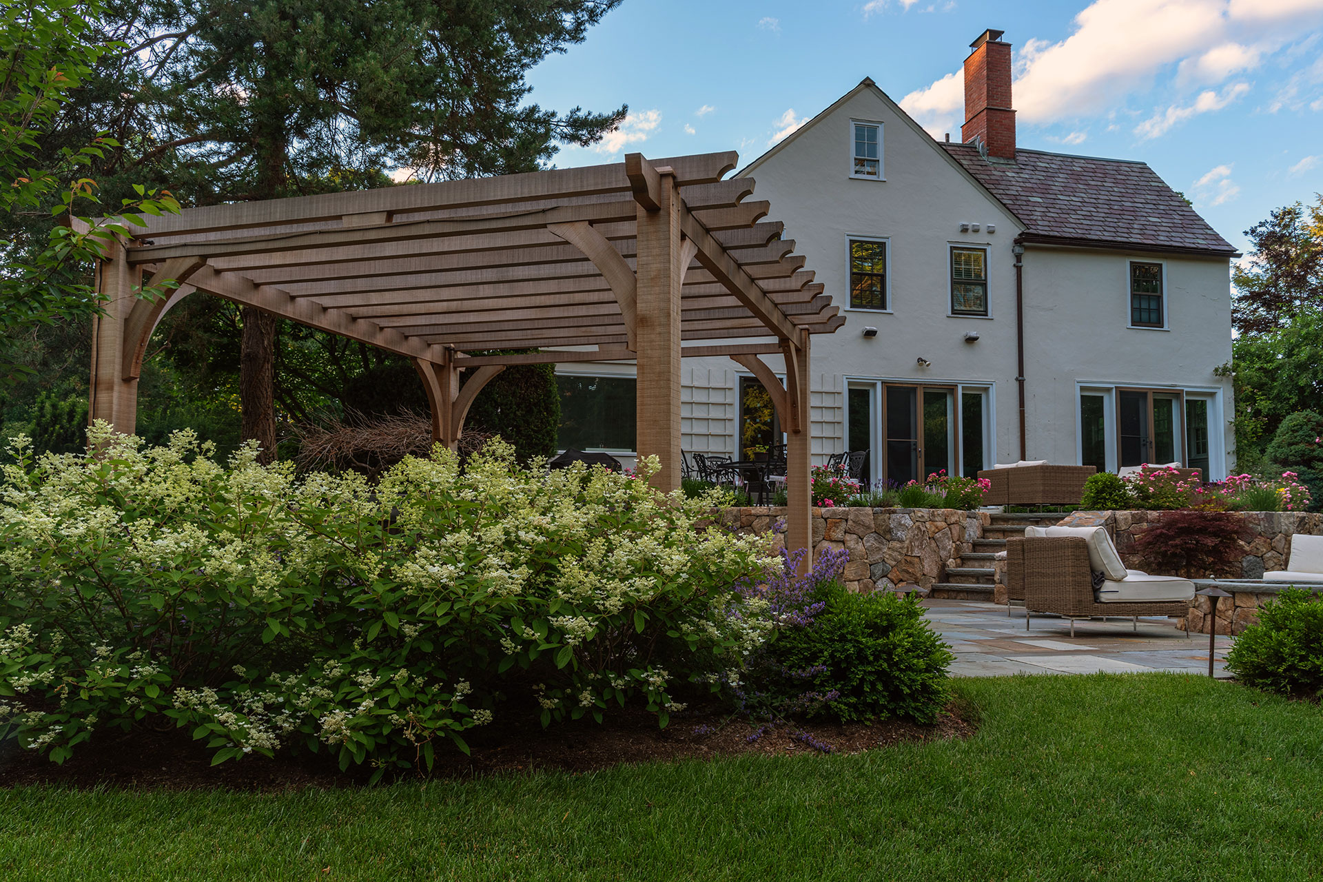 Cedar pergola enhances patio comfort with partial shade and warmth, defining seating areas without closing off the landscape.
