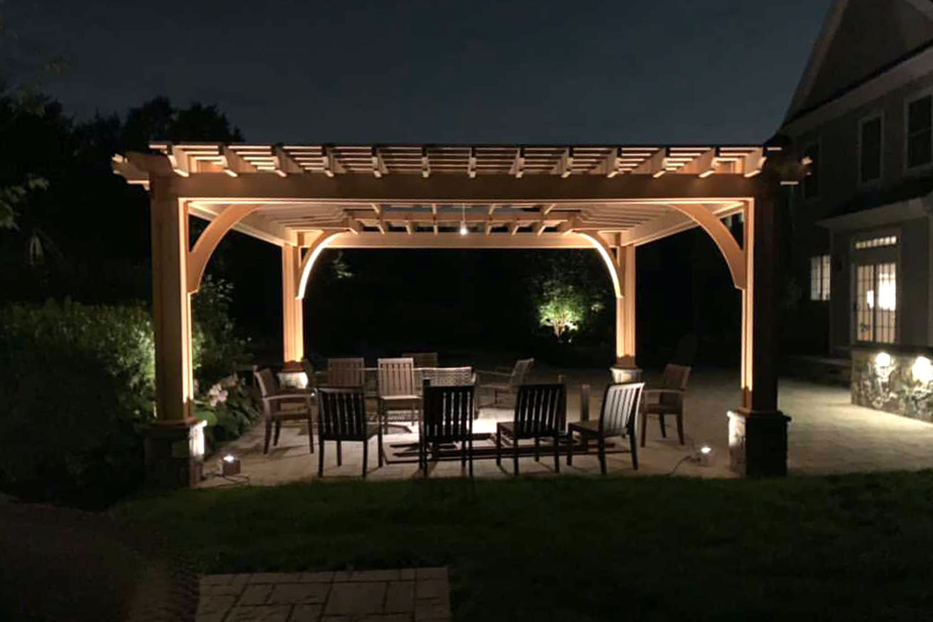 Custom wood pavilion with integrated lighting supports evening entertaining, combining warm ambiance with shelter and refined craftsmanship.
