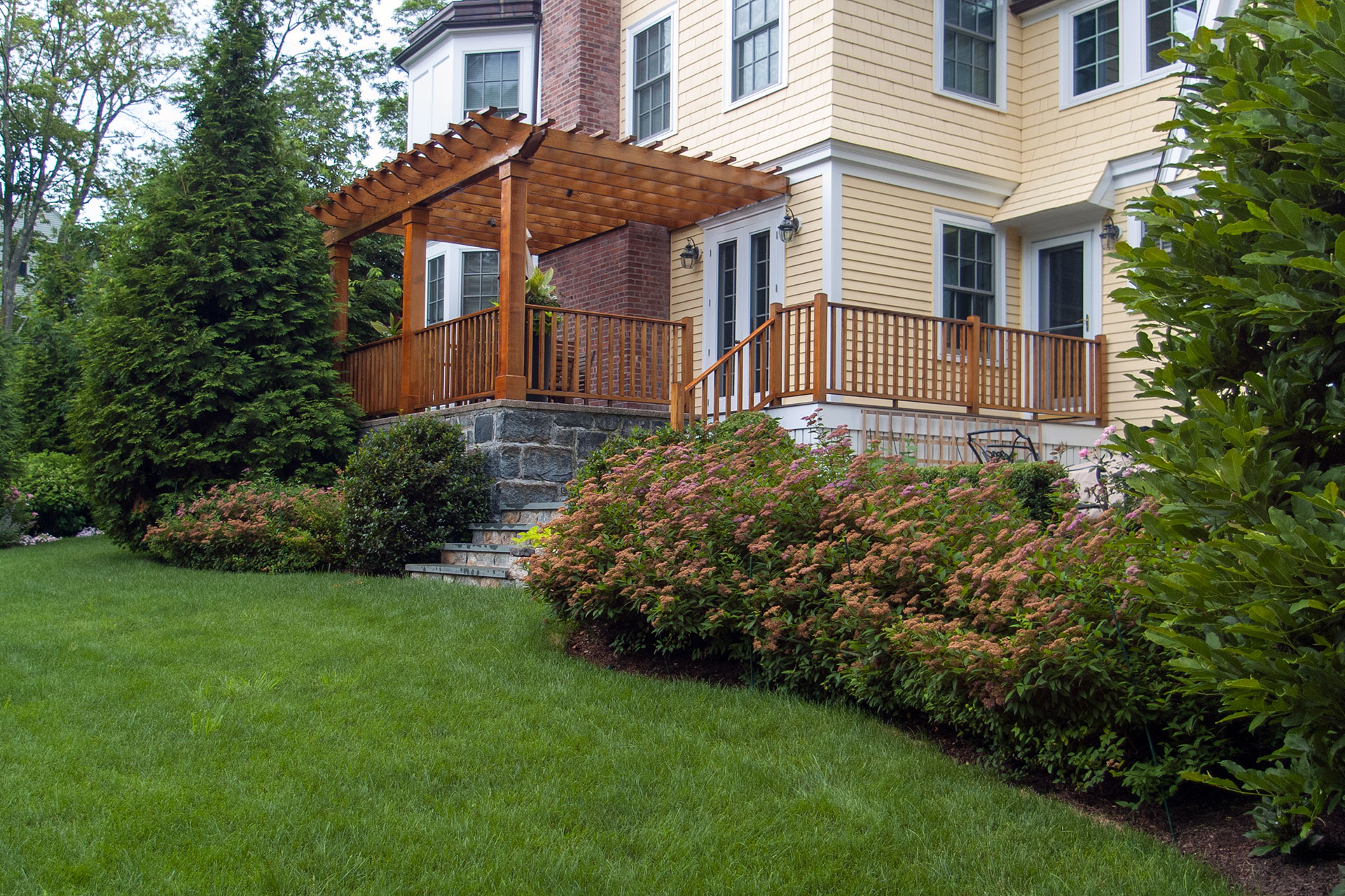 Natural wood pergola creates a private backyard retreat, adding filtered shade, warmth, and structure while blending seamlessly with surrounding plantings.