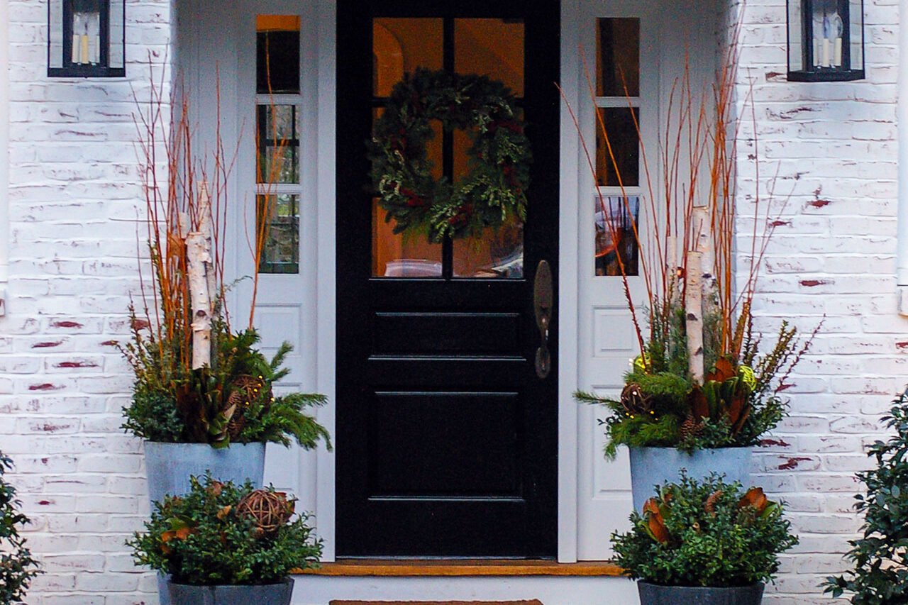 Paired entry planters display winter evergreen and branch installations; in Wellesley, MA, they offer refined seasonal interest with minimal care.