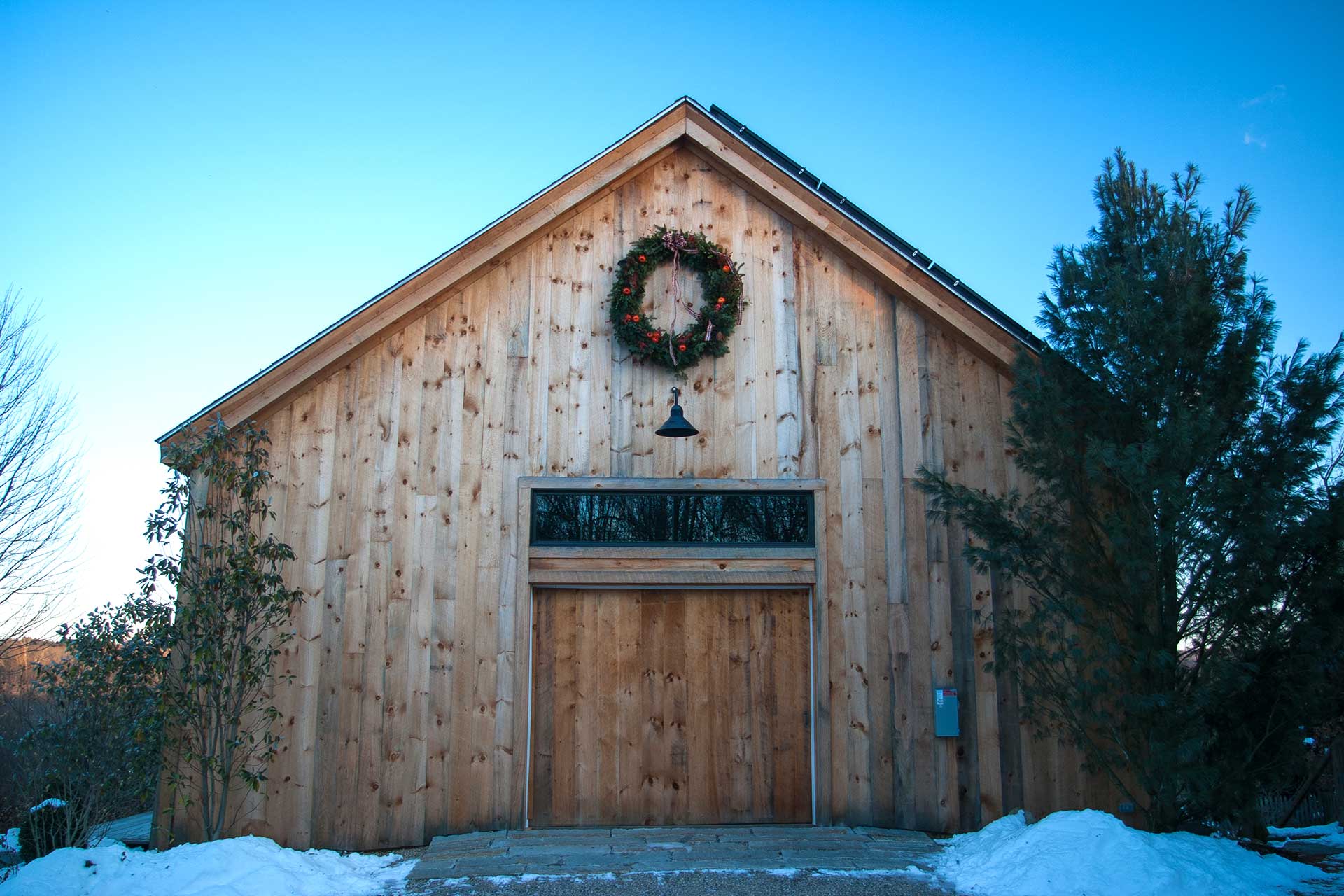 Set against rustic wood siding, this evergreen wreath adds a simple festive accent that complements the barn’s natural character.