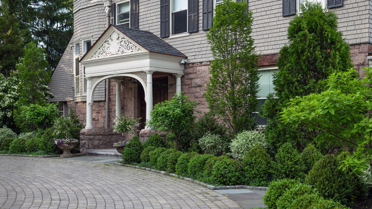 Mixed foundation shrubs surround this historic Brookline, MA entry, balancing evergreen mass with varied textures to complement architecture and create a welcoming approach.