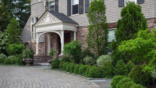Mixed foundation shrubs surround this historic Brookline, MA entry, balancing evergreen mass with varied textures to complement architecture and create a welcoming approach.