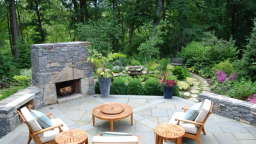transformations - after - outdoor stone fireplace with patio furniture and path to gardens