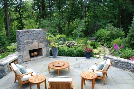 transformations - after - outdoor stone fireplace with patio furniture and path to gardens