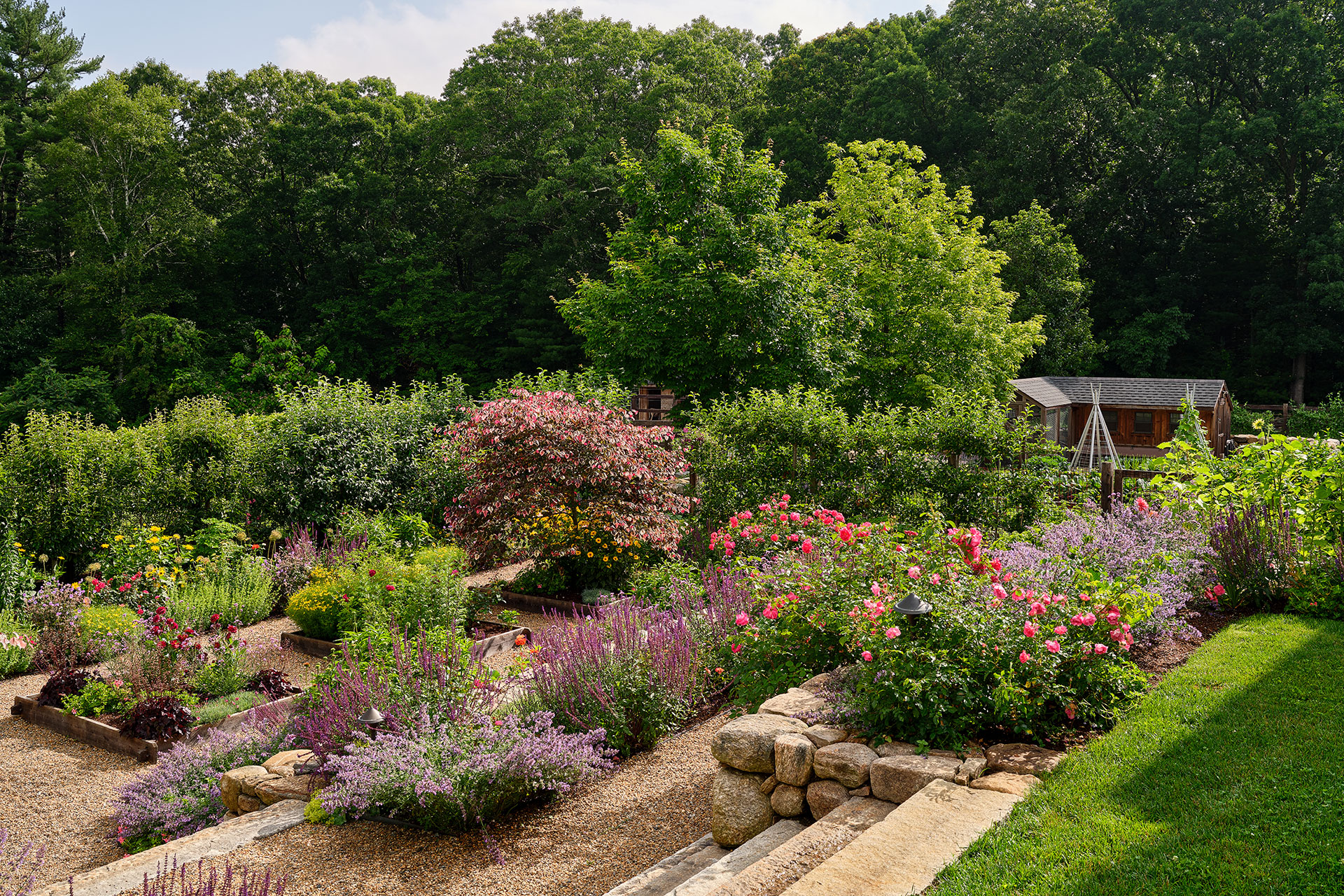 Flowering perennials mixed with vegetables attract pollinators and add seasonal interest to this New England garden.