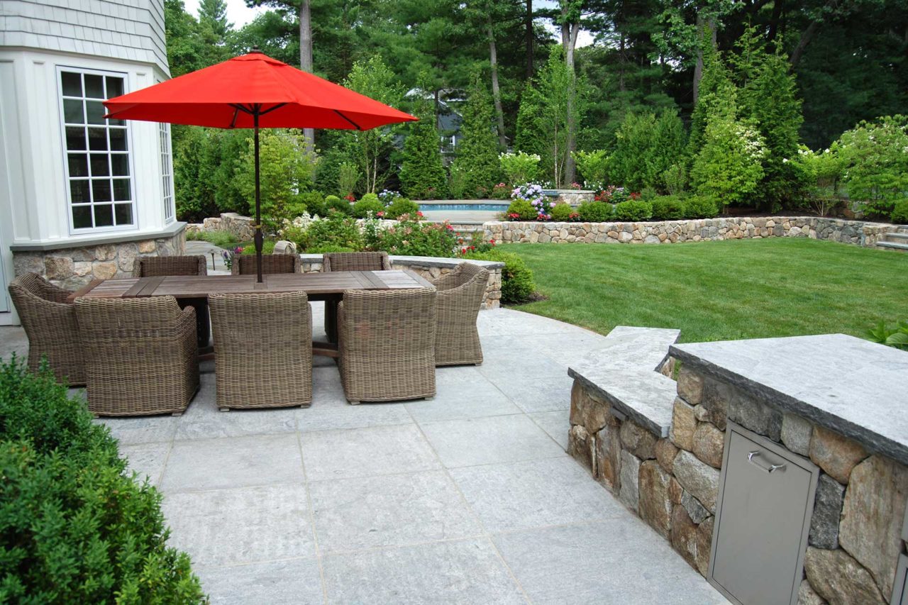 Wellesley, MA - Patio seating for 8 or more; these New England fieldstone walls double as seating walls. The umbrella provides a pop of color and a sharp contrast to surrounding materials.