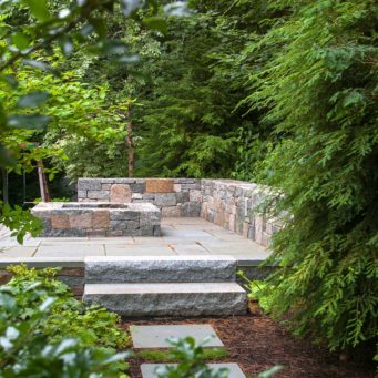 Wellesley, MA - A charming wooded path leads to this secluded stone fire pit and sitting area.